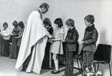 OVI-00001323 kinderen met pastoor tijdens 1e communiefeest in RKkerk